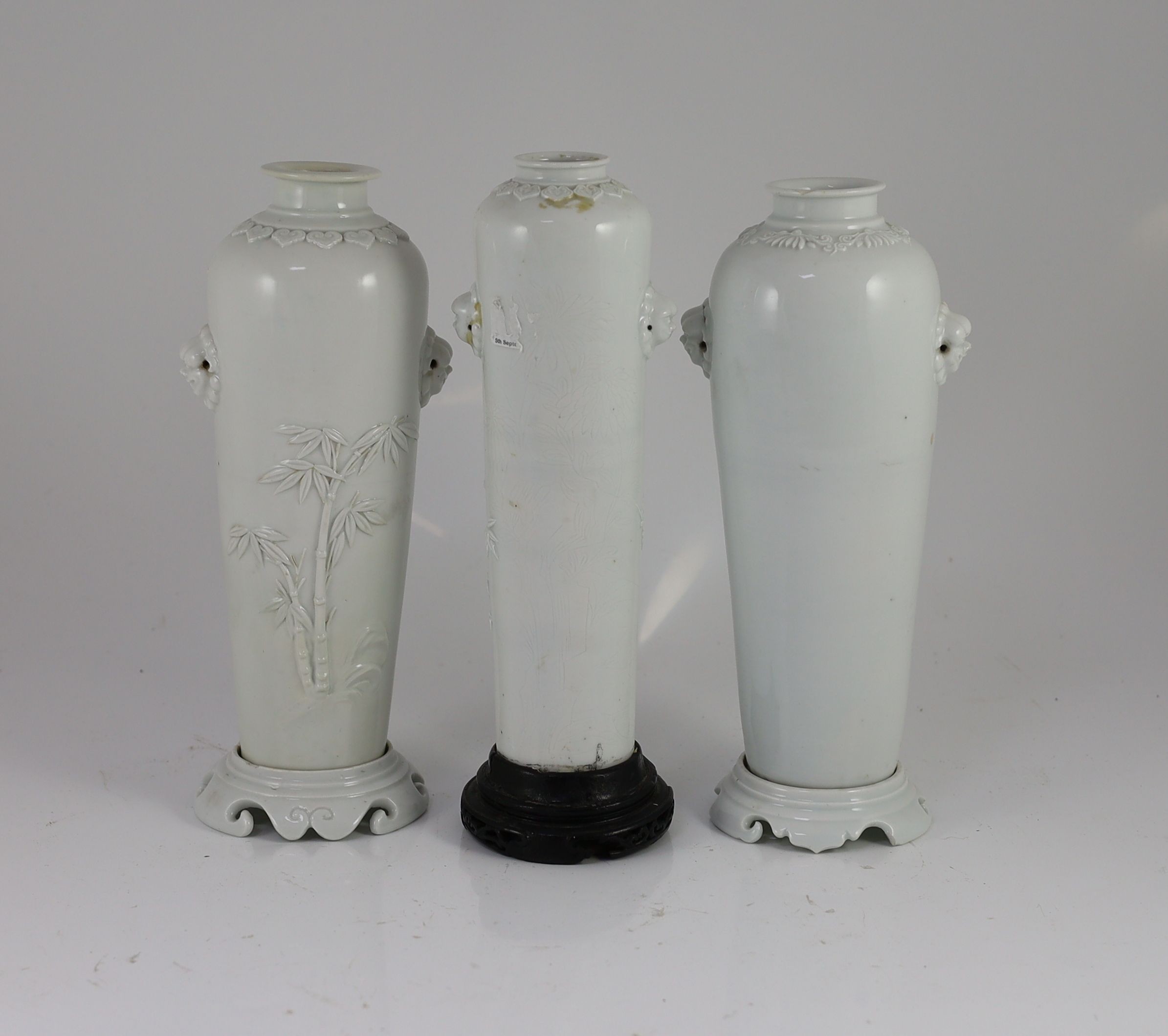 A near pair of Chinese blanc-de-chine sleeve vases with stands and a similar slender vase, Dehua kilns, 18th century Tallest 26cm high, damage